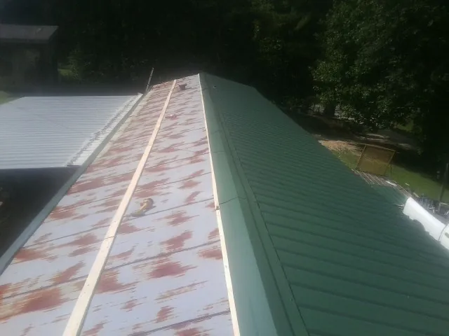 Old rusted panels beside newly installed green metal roofing — Wind Damage Roof Repair by Roofing Brothers in Glenwood Springs