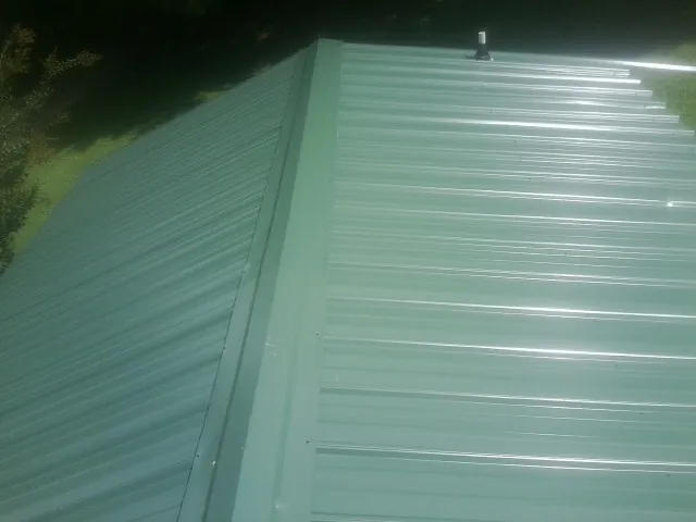 New green metal panels meeting at the ridge of a roof — Flat Roof Repair work by our crew in Glenwood Springs