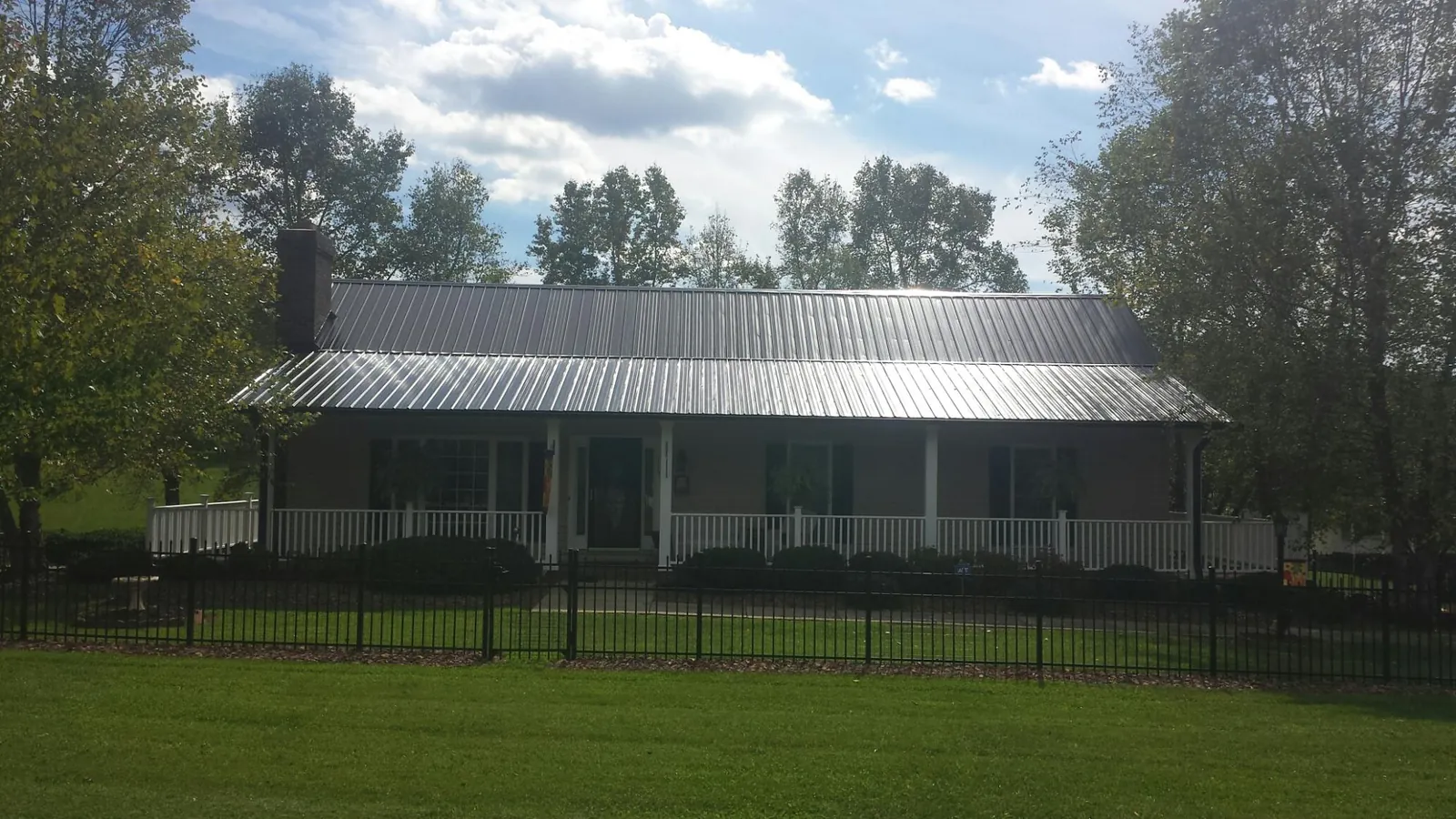 Gray metal roof on a brick ranch with a full width front porch — Gutter Guard Installation work by our crew in Glenwood Springs