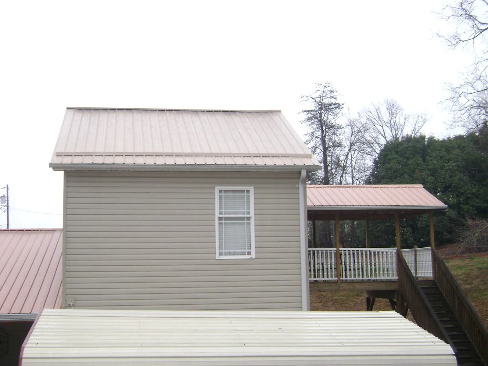 Tan metal roofs on a two story addition and attached porch, from a Roof Replacement job in Glenwood Springs