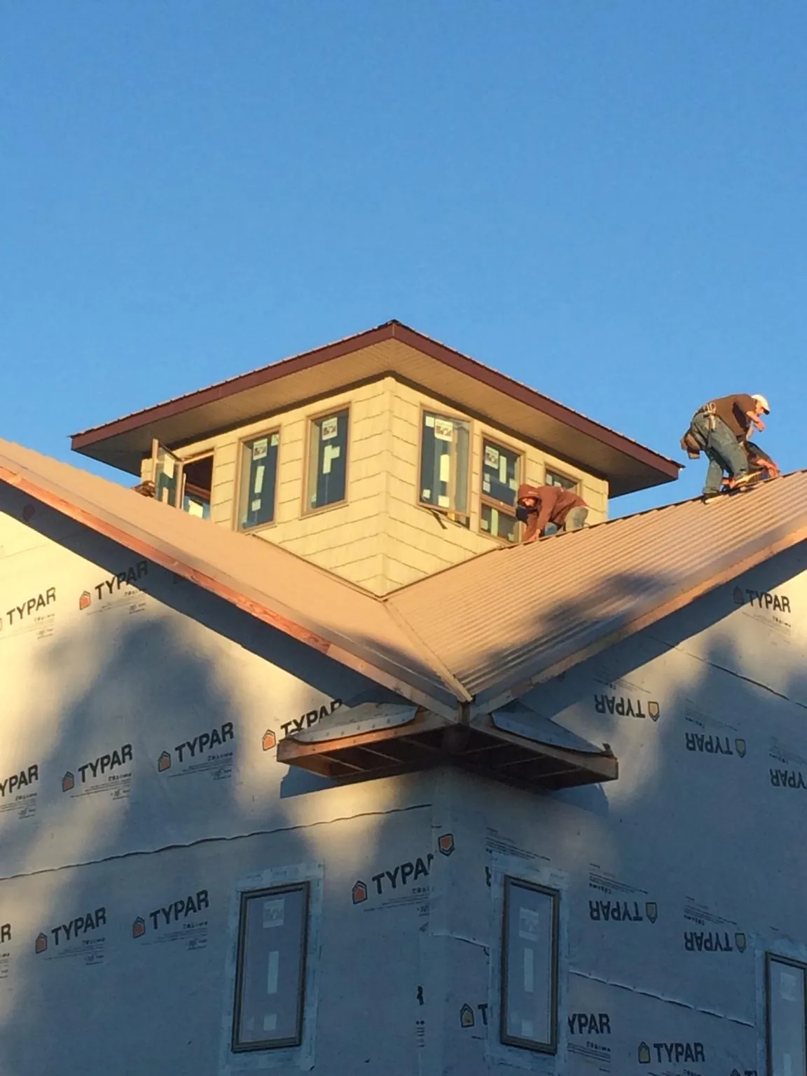 Roofers working around a rooftop cupola on a new metal roof at sunset — Roof Waterproofing in Glenwood Springs by Roofing Brothers